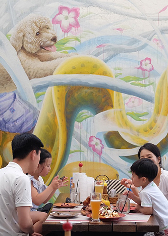 family eating lunch in the courtyard with the mural background