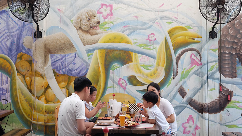 family eating lunch in the courtyard with the mural background